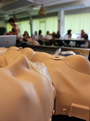 Reanimatiepoppen op een rij tijdens de training, met deelnemers op de achtergrond
